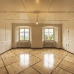 spacious room featuring a large window that allows natural light to illuminate the polished wooden floor