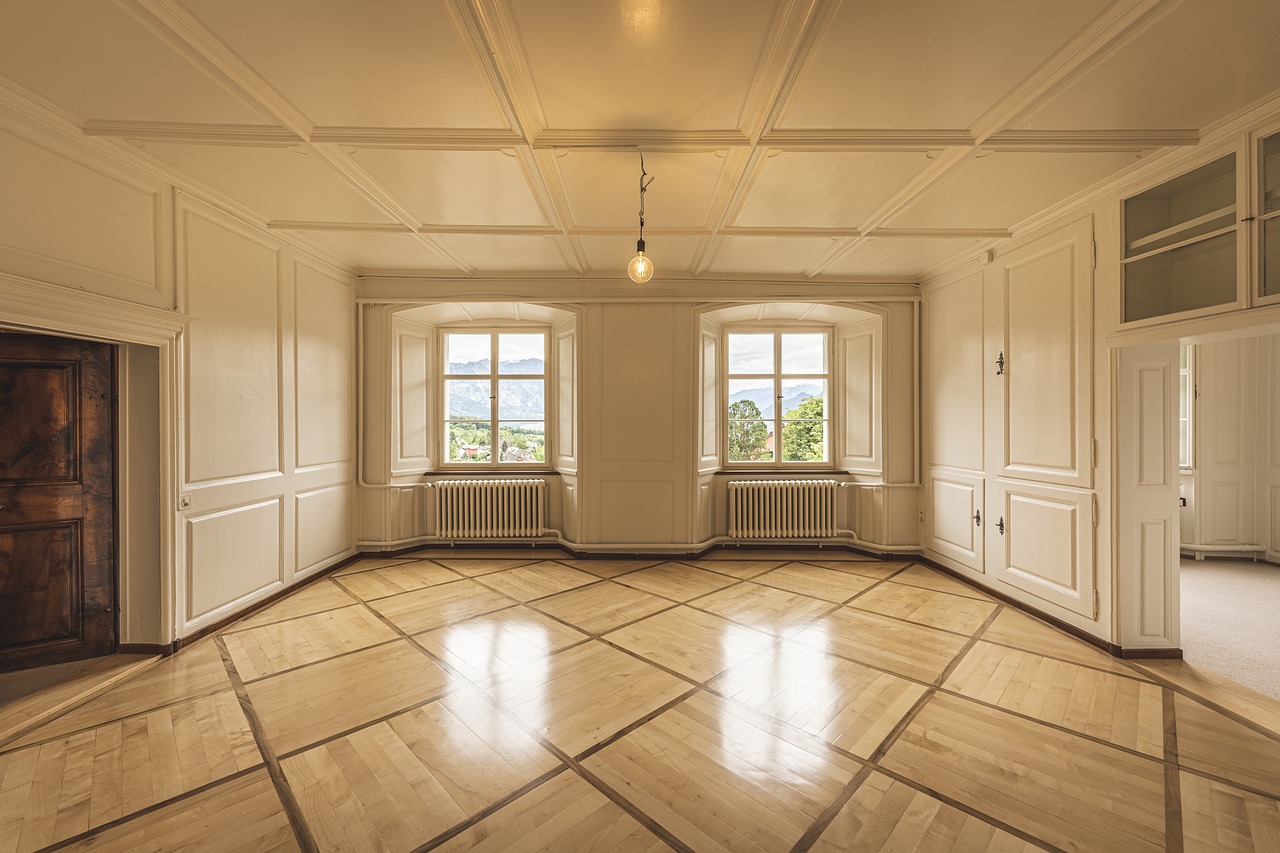 spacious room featuring a large window that allows natural light to illuminate the polished wooden floor